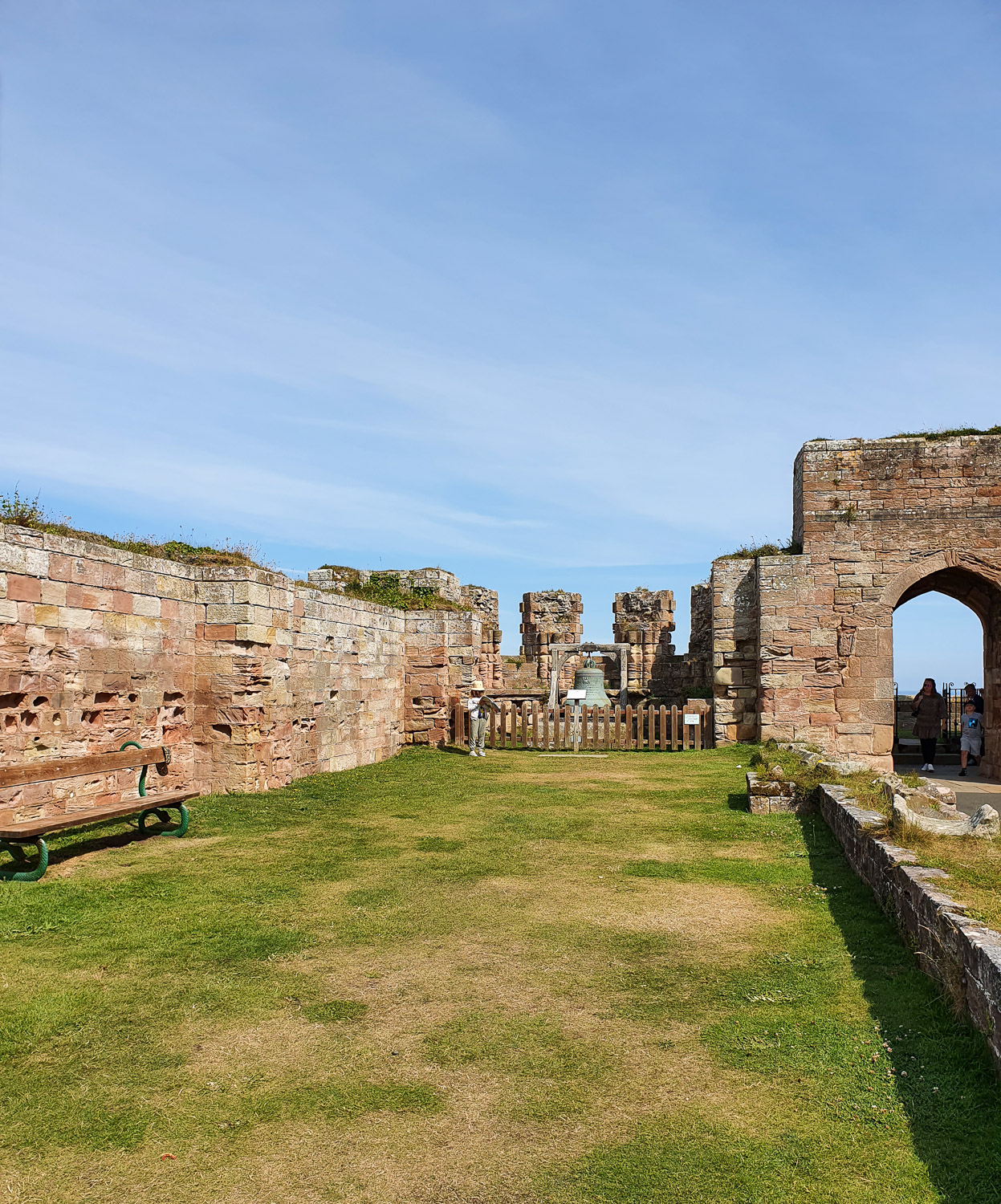 View along the grass in the ruins of the old chapel at Bamburgh Castle, Northumberland, my daughter standing at one end looking at the kids' trail in her activity book