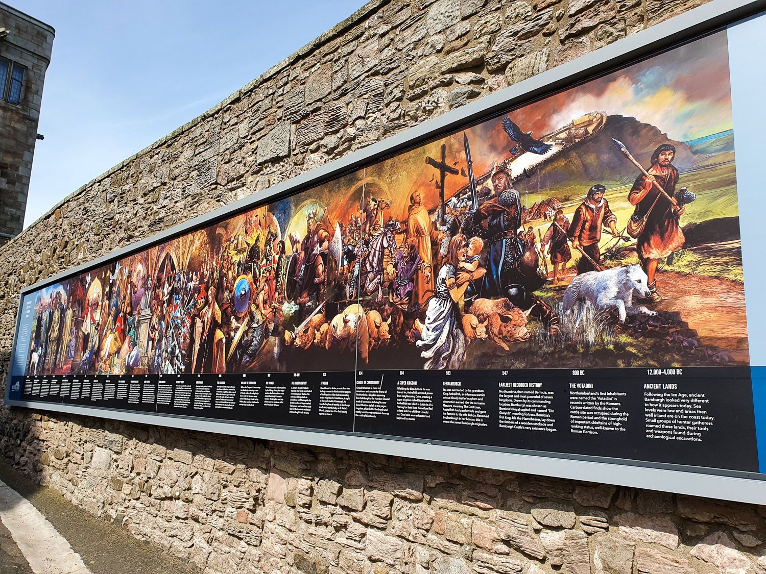 Sign with a timeline of Bamburgh Castle at the entrance to the castle buildings during a family day out in Northumberland
