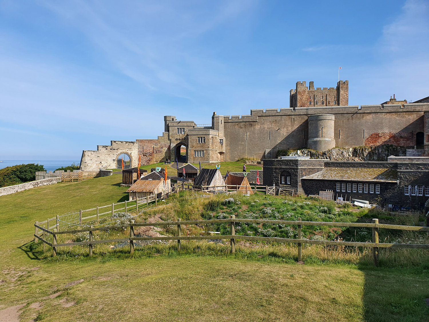 View across the huts of the Saxon village towards the gate and towers of Bamburgh Castle, Northumberland