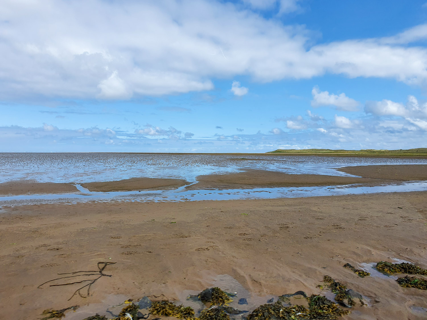 View across the mud flats and the receding water from the causeway to Lindisfarne Island during a family day out in Northumberland