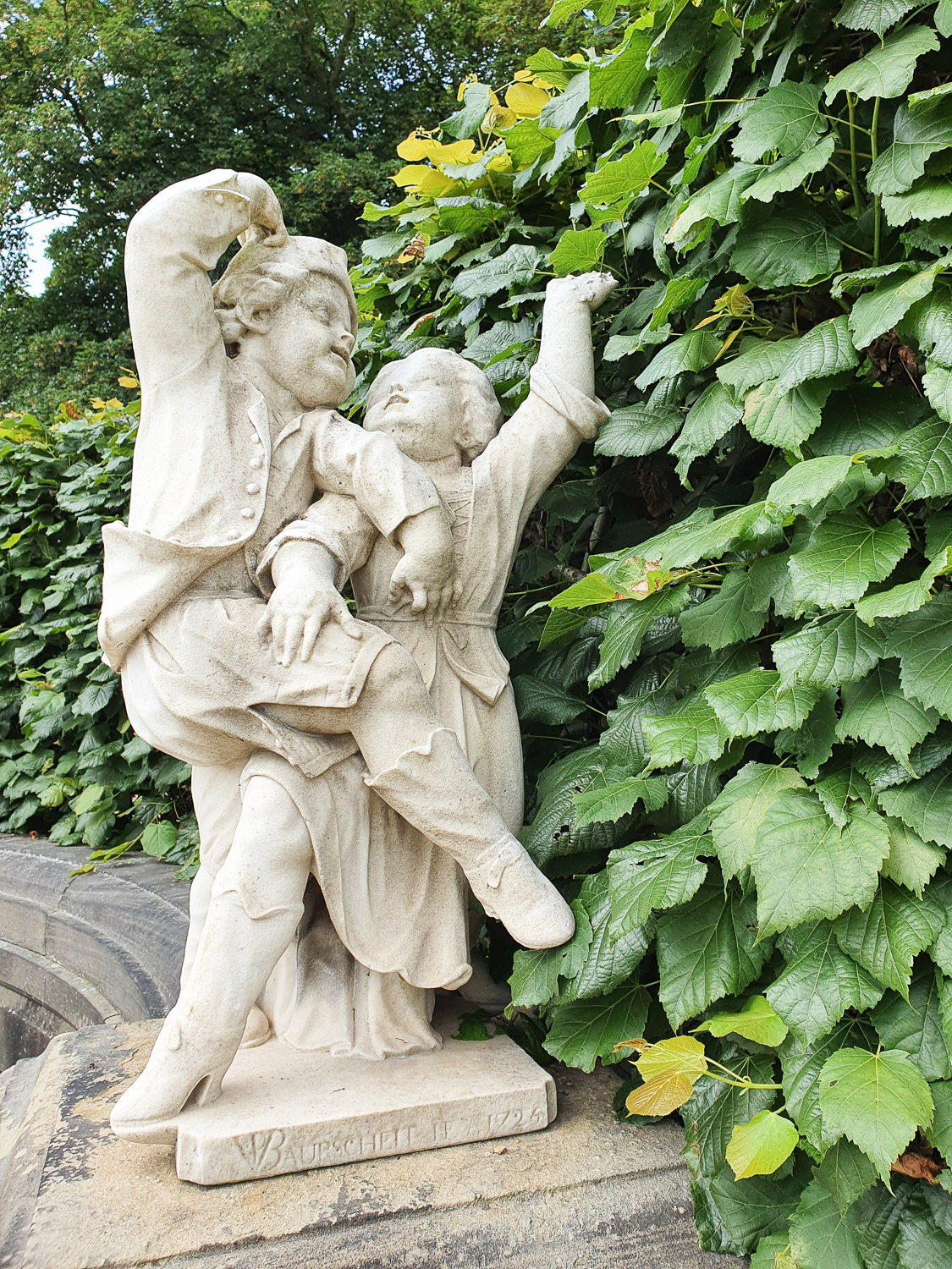 Two entwined dancing stone figures - one of the statues in the formal gardens at Harewood House near Leeds