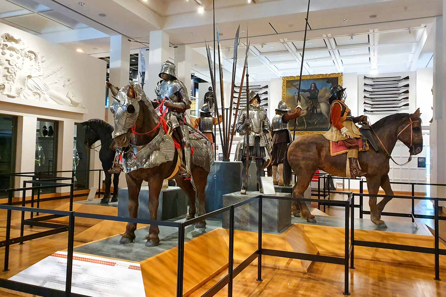 Display of men, some foot soldiers and some mounted, as well as horses in armour in one of the main display halls at the Royal Armouries