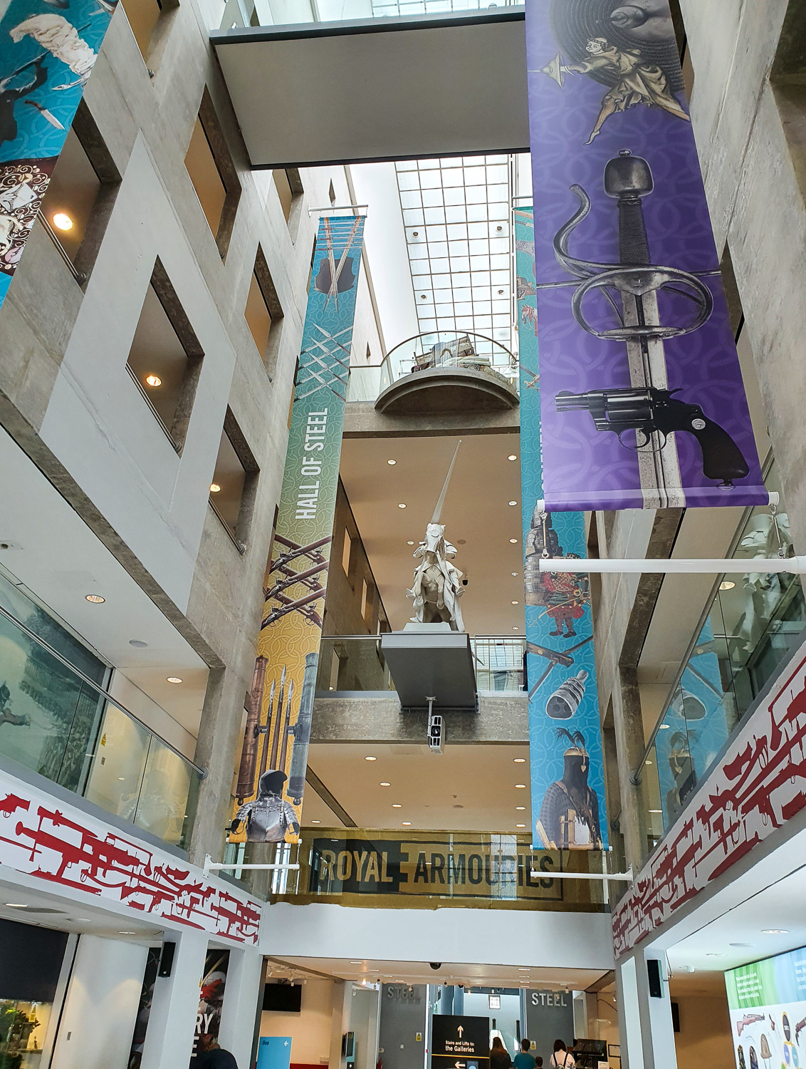 View looking up through the central hallway between the galleries at the Royal Armouries in Leeds with flags showing some of the different collections in the galleries