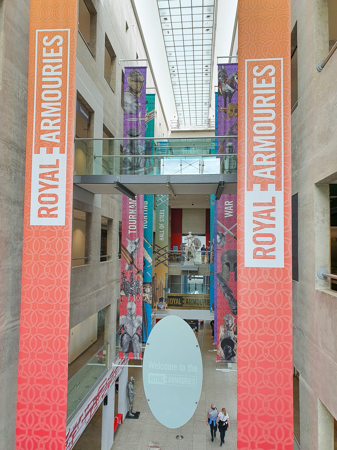 View through the central hallway between the galleries at the Royal Armouries in Leeds with flags showing some of the different collections in the galleries
