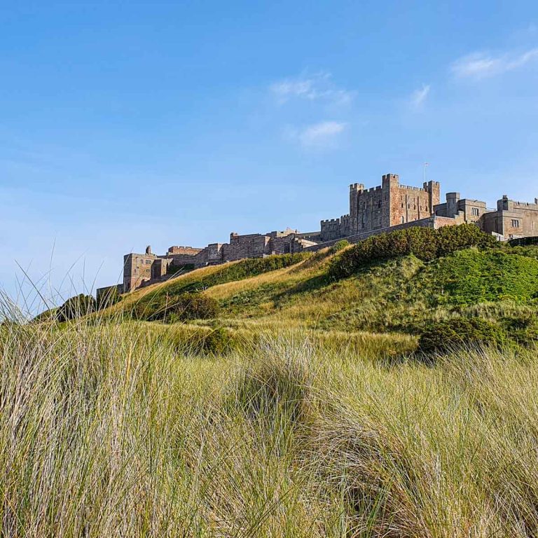 View across the dunes on the beach up towards Bamburgh Castle after a family day out in Northumberland