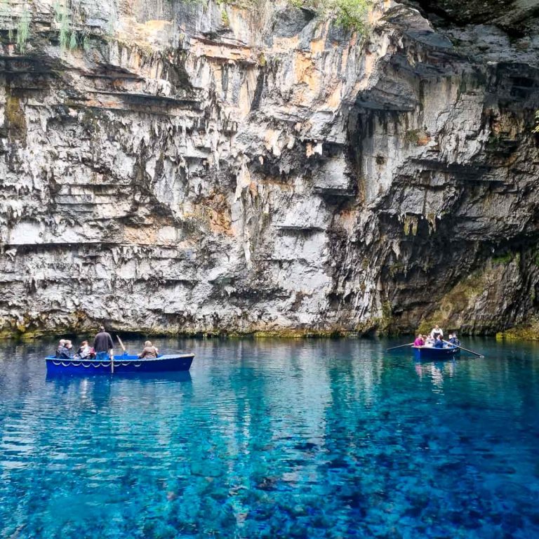 Two small blue rowing boats full of tourists on the clear turquoise blue water of Melissani Lake in Kefalonia; Melissani Cave is one of the biggest tourist attractions in Kefalonia with kids