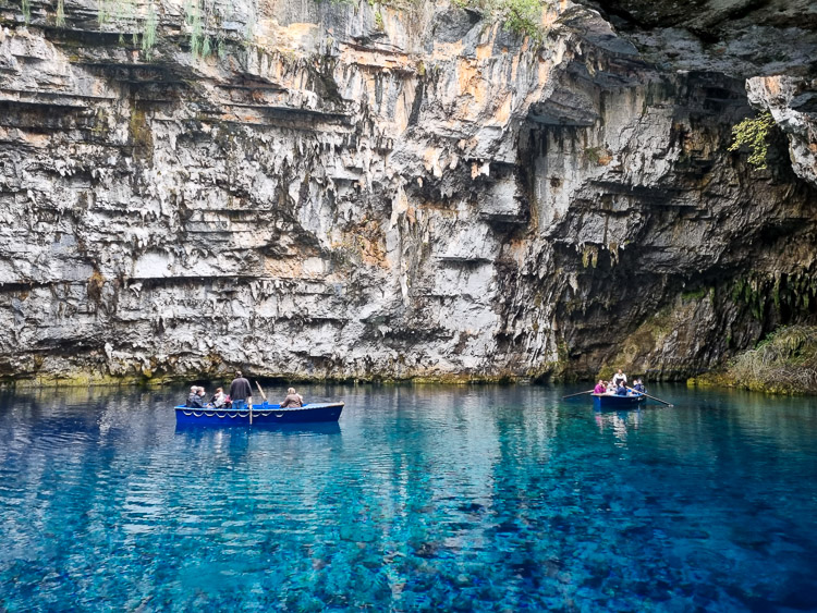 Two small blue rowing boats full of tourists on the clear turquoise blue water of Melissani Lake in Kefalonia; Melissani Cave is one of the biggest tourist attractions in Kefalonia with kids