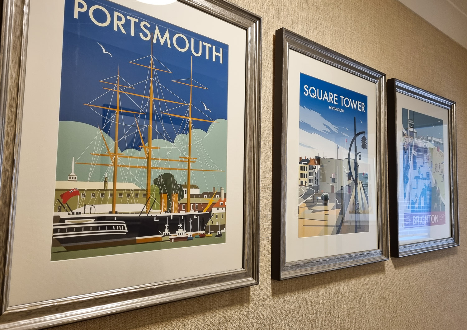 Retro style artwork of locations in Portsmouth decorating the hallway by the penthouse at the Beachcroft hotel Felpham - my review of a stay at the Sussex hotel with kids