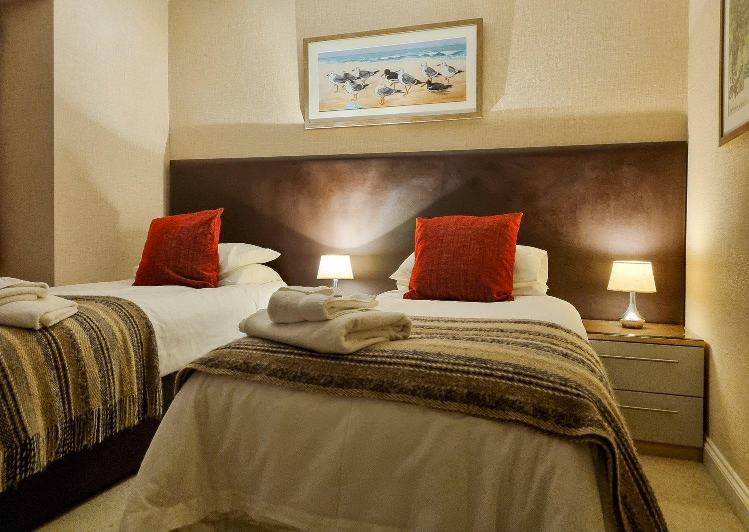 Twin beds with red cushions and seagull artwork in the second bedroom of the penthouse at the Beachcroft hotel Felpham - my review of a stay at the Sussex hotel with kids