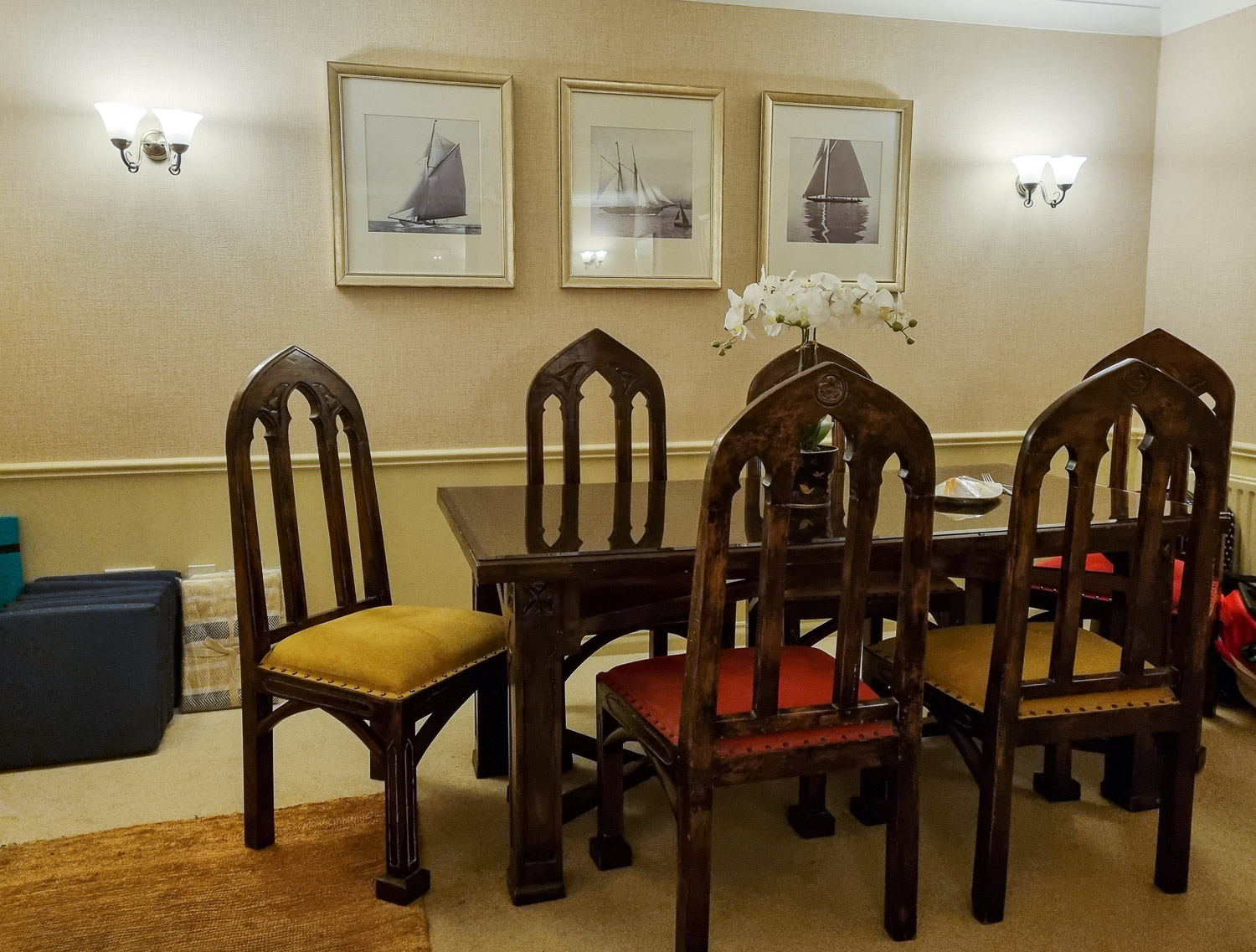 Brown wood dining table with with matching chairs including red and yellow seats in the penthouse at the Beachcroft hotel Felpham - my review of a stay at the Sussex hotel with kids
