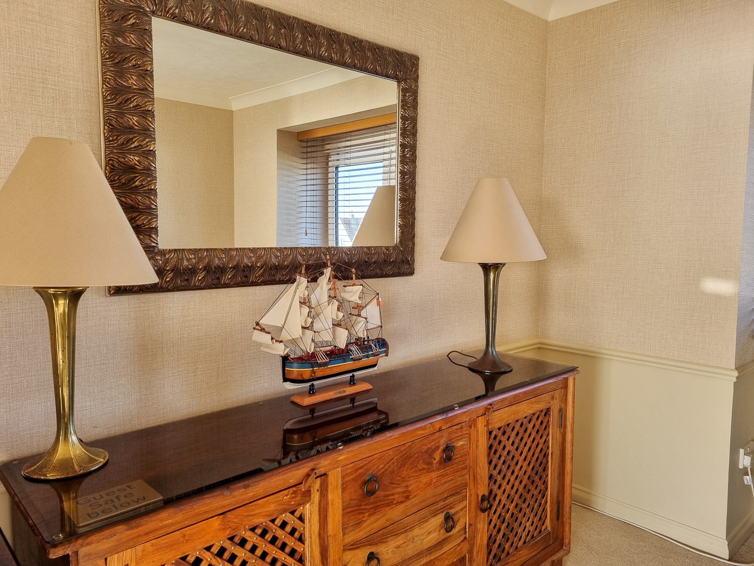 Model ship on a wooden cabinet flanked by lamps under a mirror in the penthouse at the Beachcroft hotel Felpham - my review of a stay at the Sussex hotel with kids