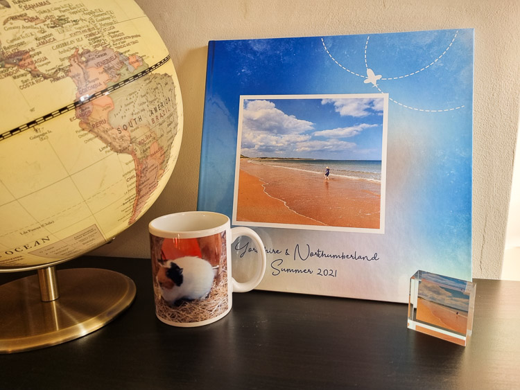View of several products from the photo printing range from My Picture including mug, MixBlox acrylic photo block and photobook featuring a girl on a beach, next to a globe - My Picture review