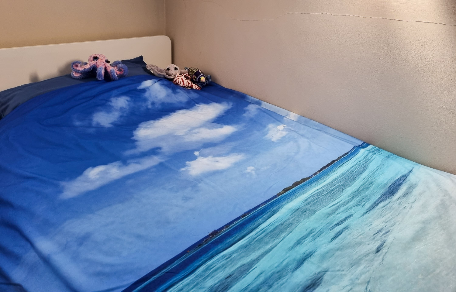 View of single duvet cover printed with a photo of the Caribbean sea with stuffed toys in the corner - testing the photo printing services for my My Picture review