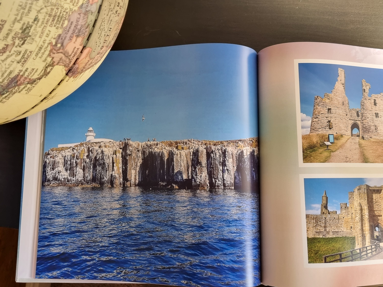 Open photo book showing photos of a family holiday in Northumberland, and a globe just seen, created as part of my My Picture review of photo printing services
