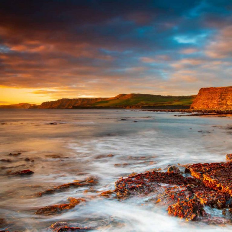 A view across Kimmeridge Bay on the Jurassic Coast at sunset - fossil hunting tops my list of the best things to do in Dorset with kids