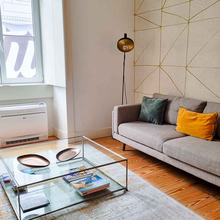 View of glass coffee table, grey armchair and velvet cushions with anglepoise lamp and geometric wallpaper behind - testing out the family-friendly accommodation for my Plum Guide review of our self-catering Lisbon apartment