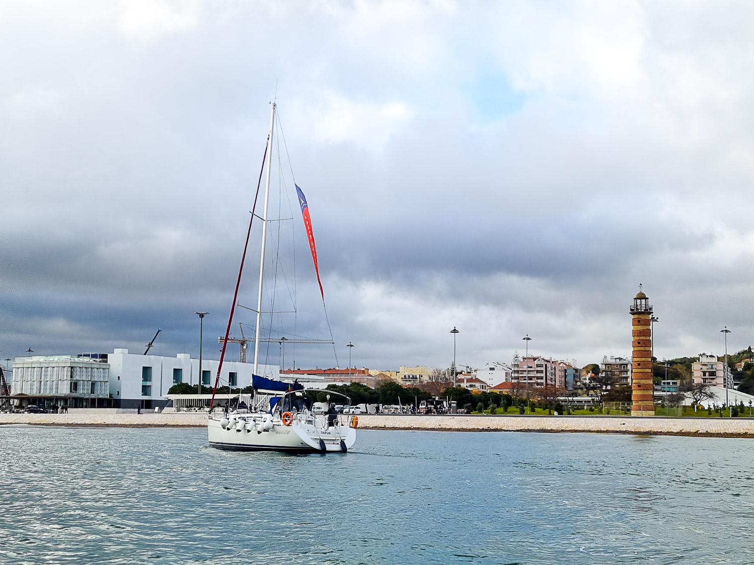 View of a yacht on the river Tagus with a lighthouse tower on the bank - my review of our Lisbon Hippotrip amphibious tour