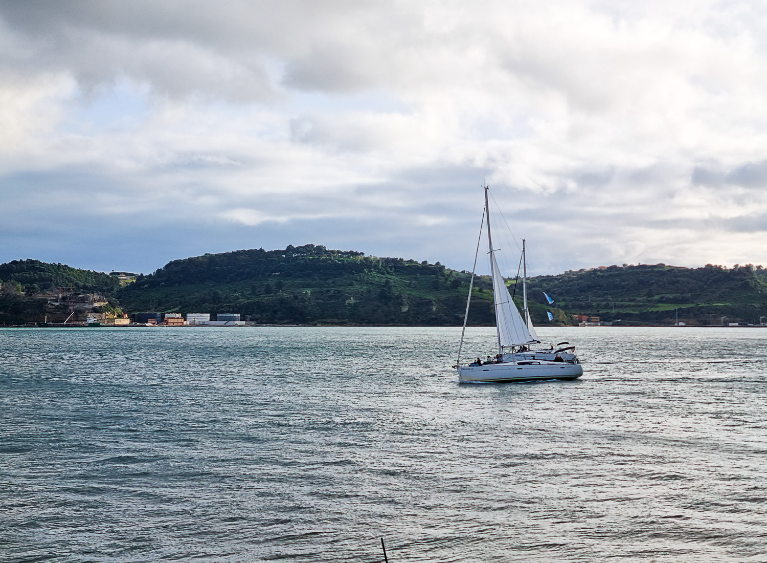 View of a yacht on the water of the river Tagus and the wooded hills on the opposite bank from Lisbon and Belem, seen from the river during our Hippotrip tour of Lisbon with kids
