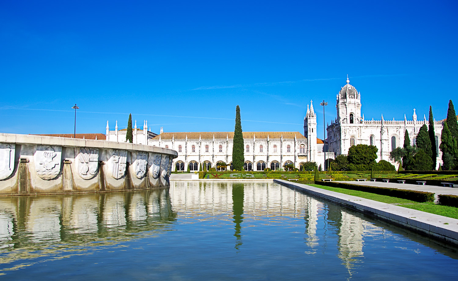 View across the pool of a fountain and gardens to the Jeronimos Monastery - there are plenty of green spaces and gardens to relax if you're visiting Belem with kids