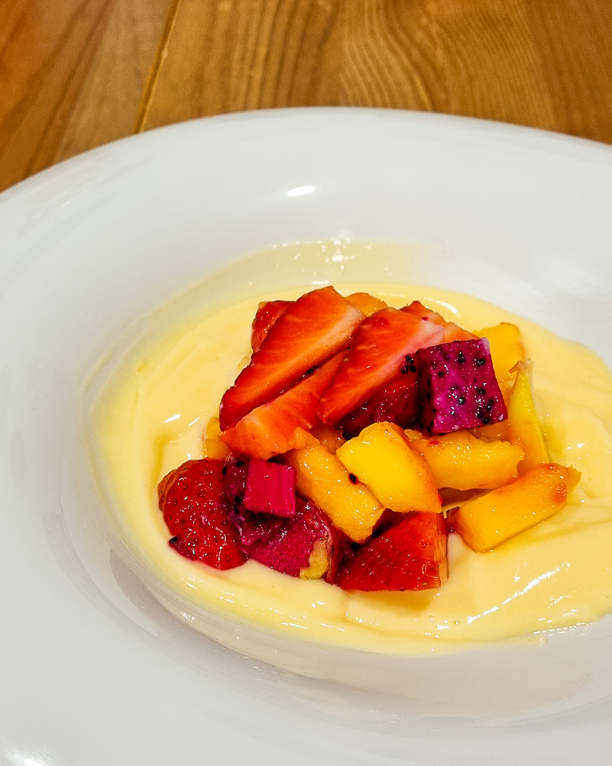 Bowl of freshly made custard with strawberries, purple dragon fruit and mango on top - our dessert made as part of our Lisbon cooking class for families