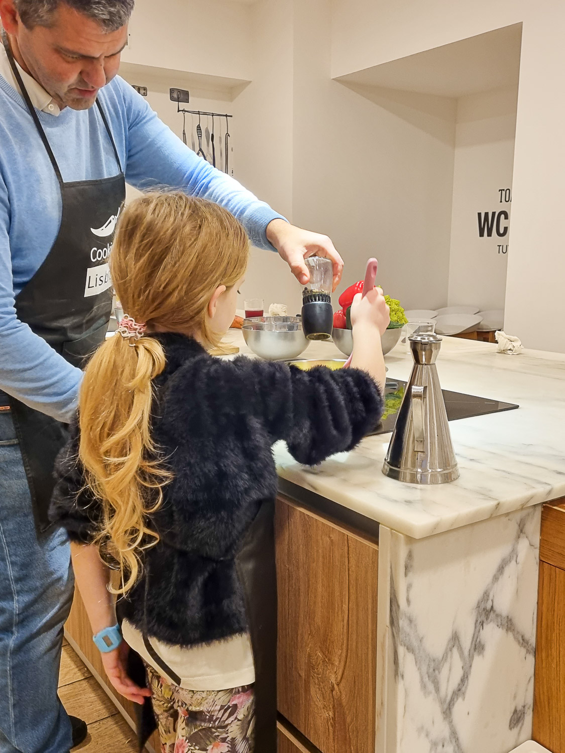 Chef Miguel helps my daughter begin the cooking at the little stove in the Cooking Lisbon kitchen, during our market tour and cooking workshop with kids