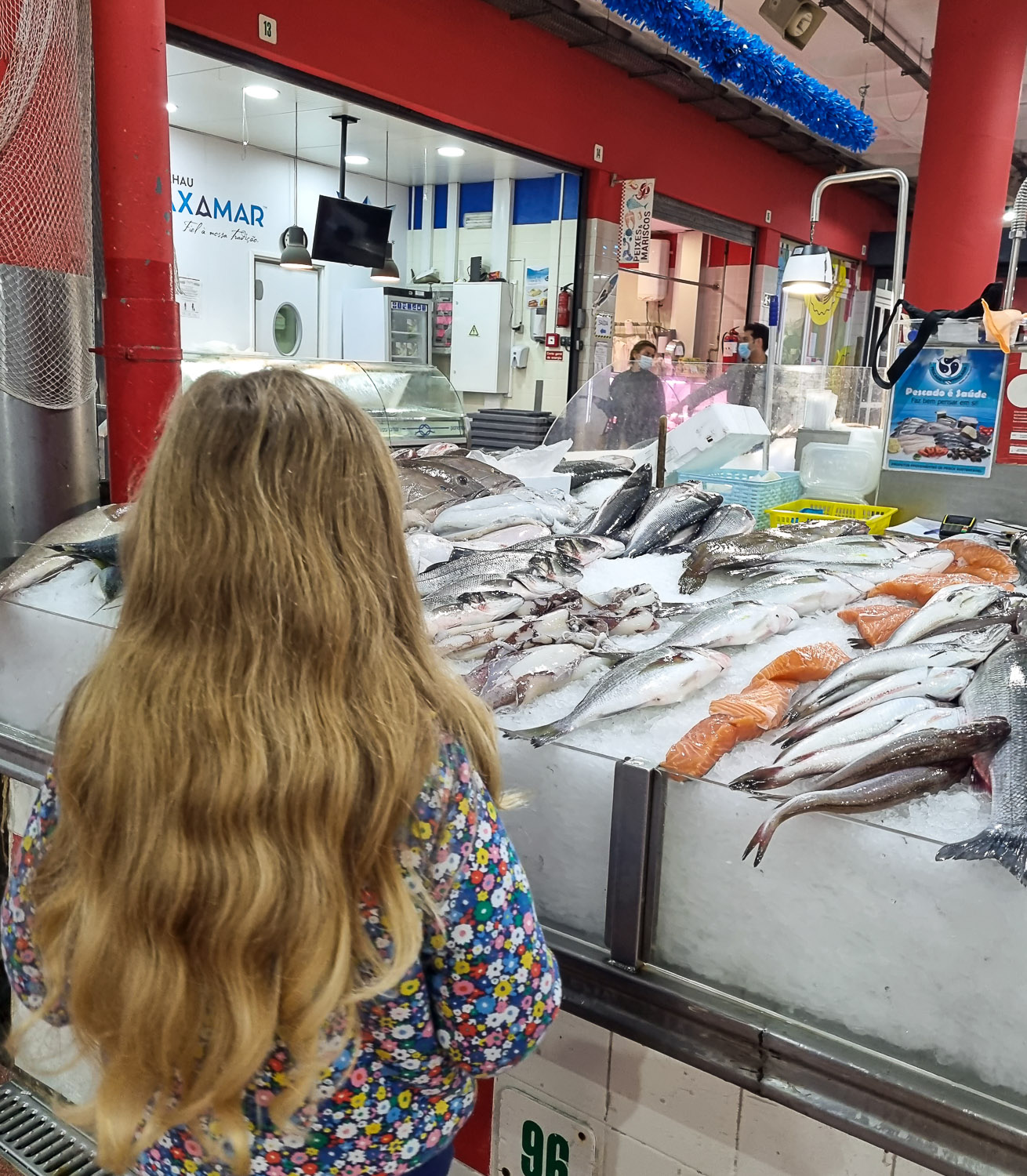 My daughter looks at the fresh fish laid out on ice at one of Lisbon's markets, buying ingredients for our Lisbon cooking workshop with kids