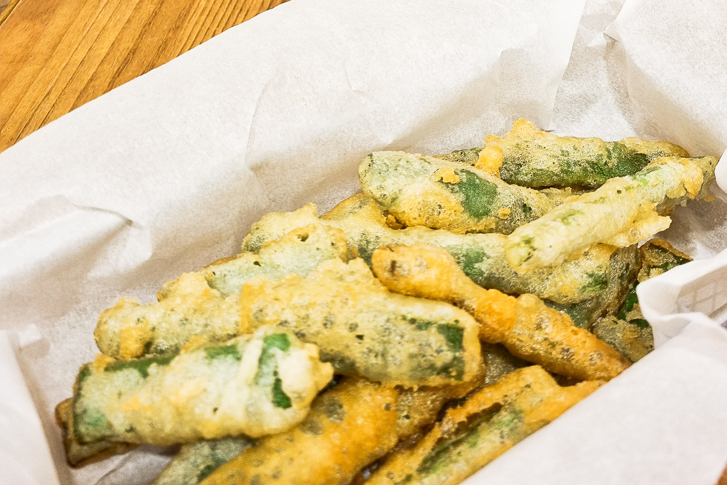 Basket of tempura green beans wrapped in greaseproof paper on a table, created during our Lisbon family cooking class