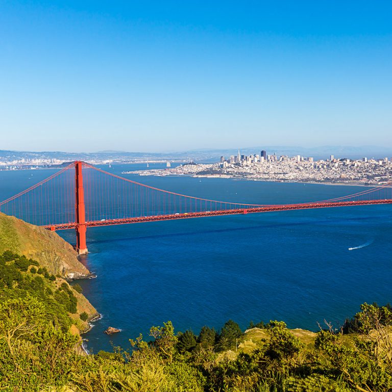 View out to the Golden Gate Bridge from the Marin Headlands in California on a sunny day, with San Francisco visible in the background - with hikes and views, it's one of the easiest day trips from San Francisco with kids