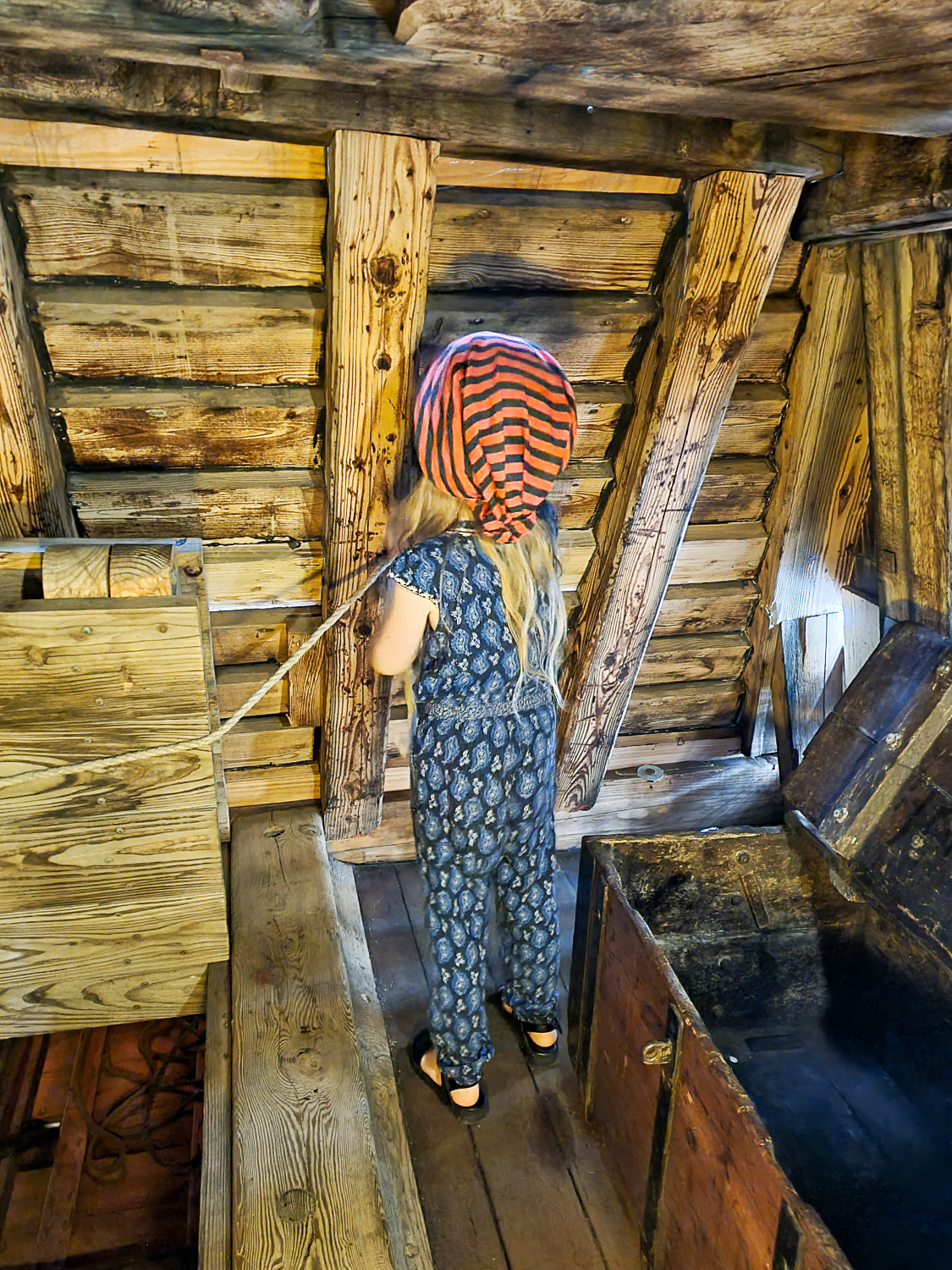 My daughter wearing her stripy covered protective helmet and holding a rope in part of the Golden Hinde - my review of Escape from the Golden Hinde with kids