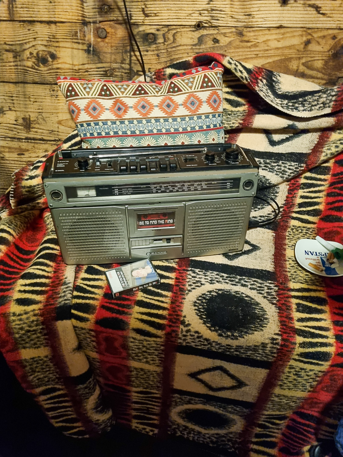 Old-fashioned tape player and tape on a pattered blanket and cushion in the hold of the Golden Hinde - my Escape from the Golden Hinde review of a new escape room in London with kids