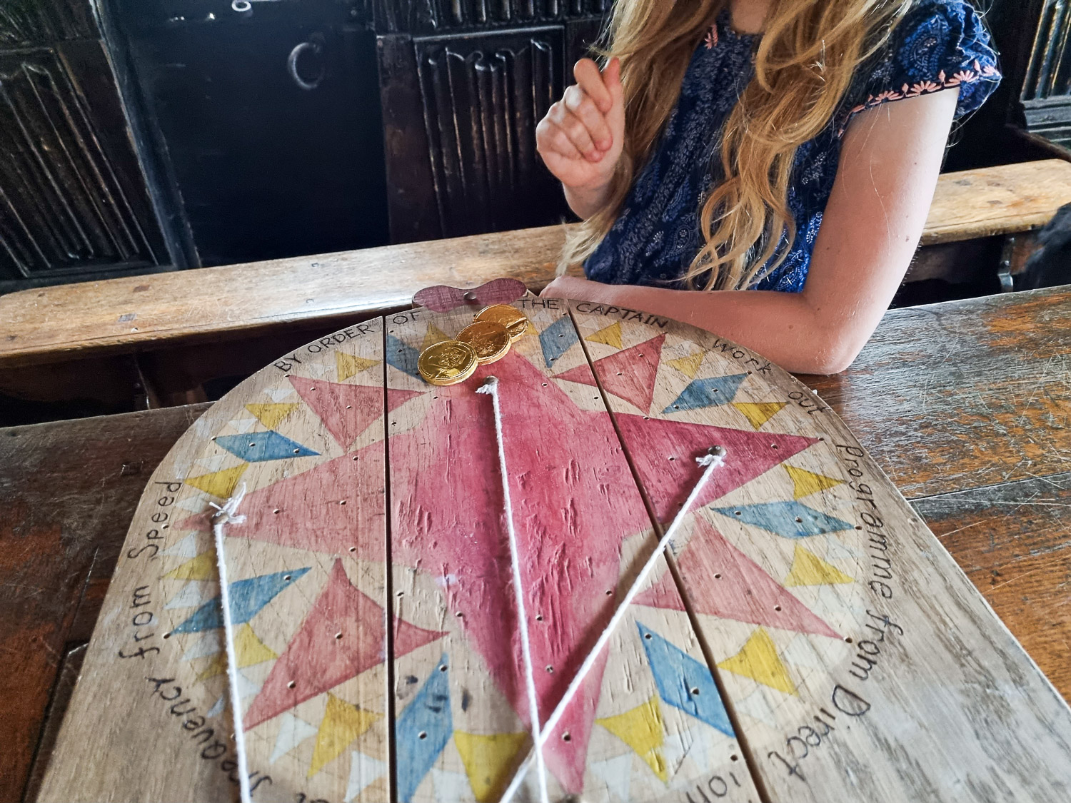 My daughter with some of the chocolate coin treasure and colourful wooden compass design during Escape from the Golden Hinde with kids - my review