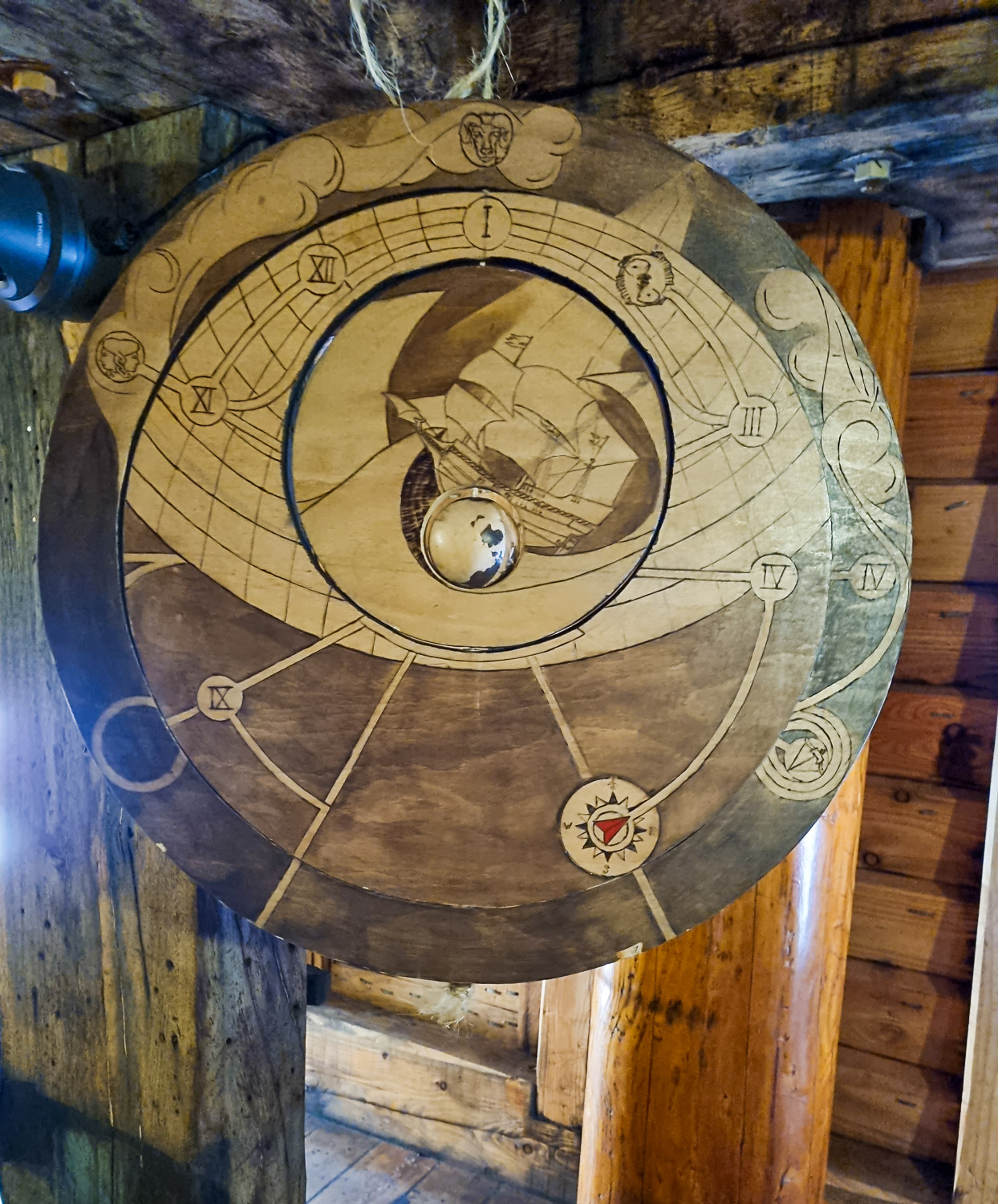 View of a suspended wooden disc with symbols and Roman numerals on, part of the Golden Hinde escape room - my review of Escape from the Golden Hinde with kids