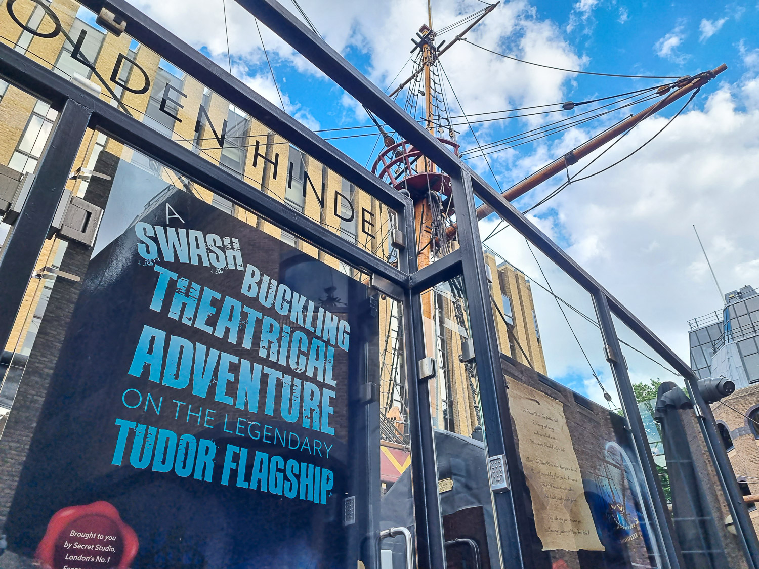Sign for the new Golden Hinde escape room on the side of the replica Tudor galleon, masts seen against the blue sky - my Escape from the Golden Hinde review