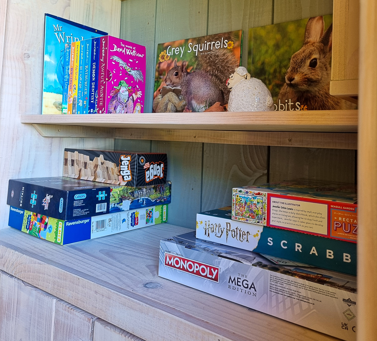 Shelf with board games, puzzles and books in the family shepherd's hut - perfect for a stay at Dittisham Hideaway with kids