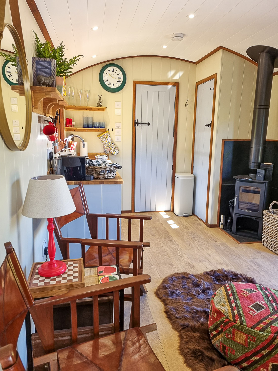 View of the living space and kitchen, with stove, looking towards the bathroom door, in one of the shepherd's huts at Dittisham Hideaway - my review of the Devon luxury glamping site