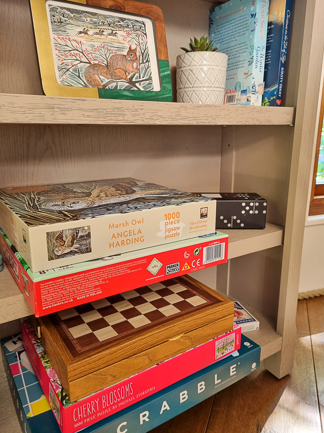 Set of shelves with board games, jigsaws and books in Owl treehouse - my review of Dittisham Hideaway with kids