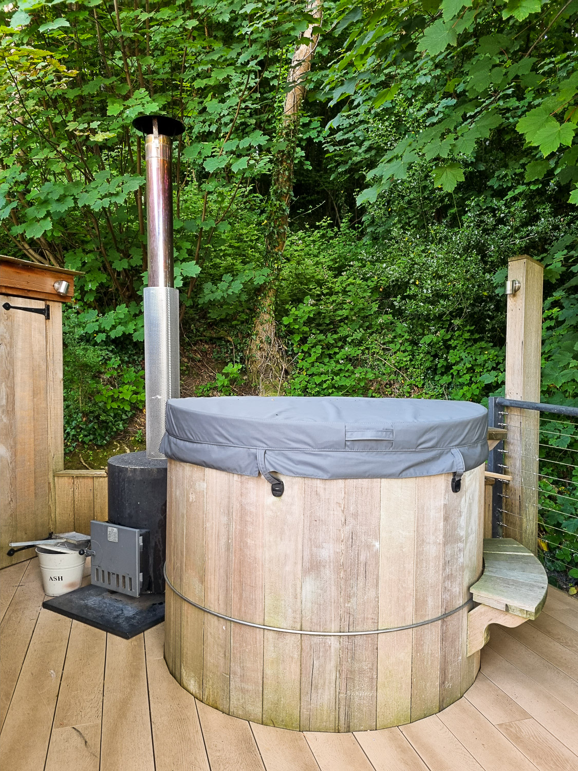 Wood-fired hot tub on the deck of Owl Treehouse, with a cover over the wooden hot tub - my review of Dittisham Hideaway with kids after a stay at the luxury Devon glamping site