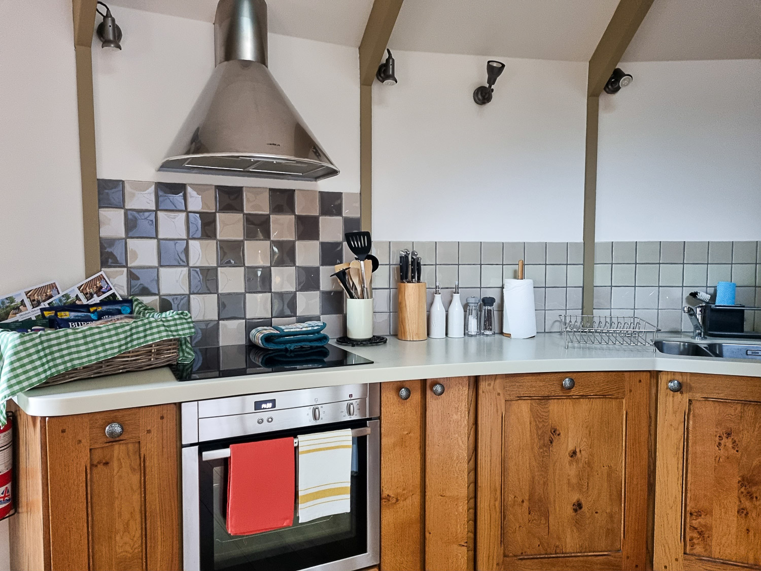 View of part of the kitchen at owl treehouse with oven, hamper, dishwasher and kitchen utensils- my Dittisham Hideaway review