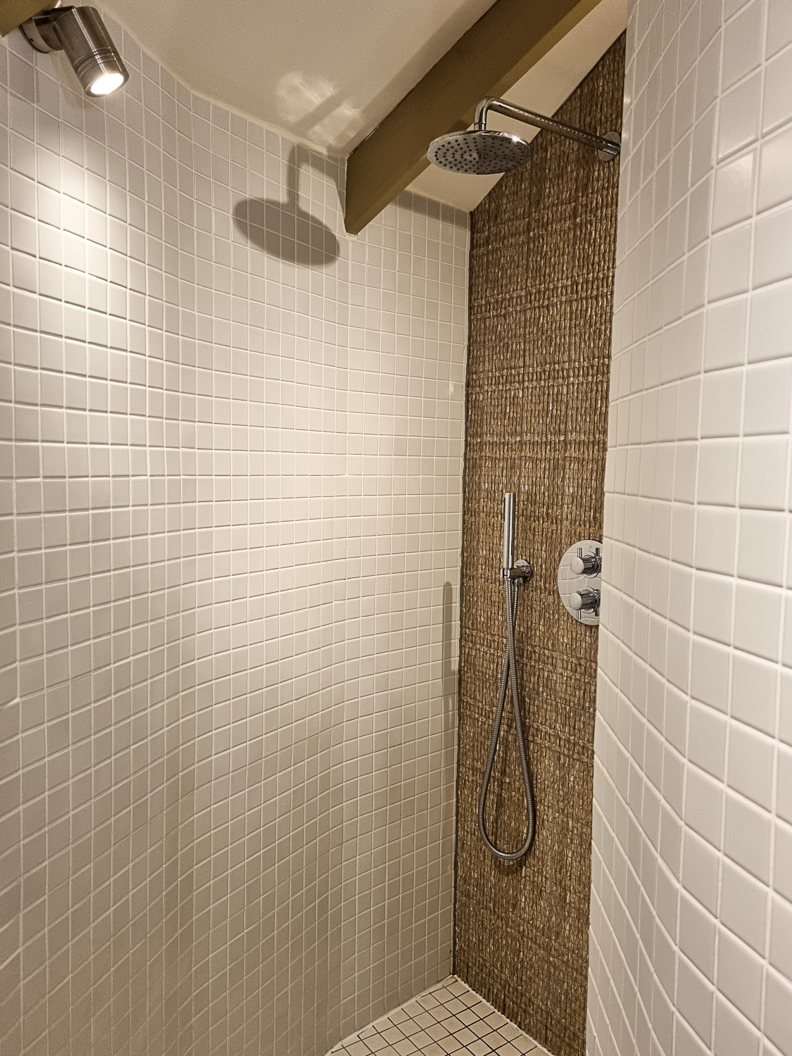 View of one of the showers, attached to the sleeping area, with neutral tiles and natural materials on the far wall - my Dittisham Hideaway review after a luxury glamping break in Devon
