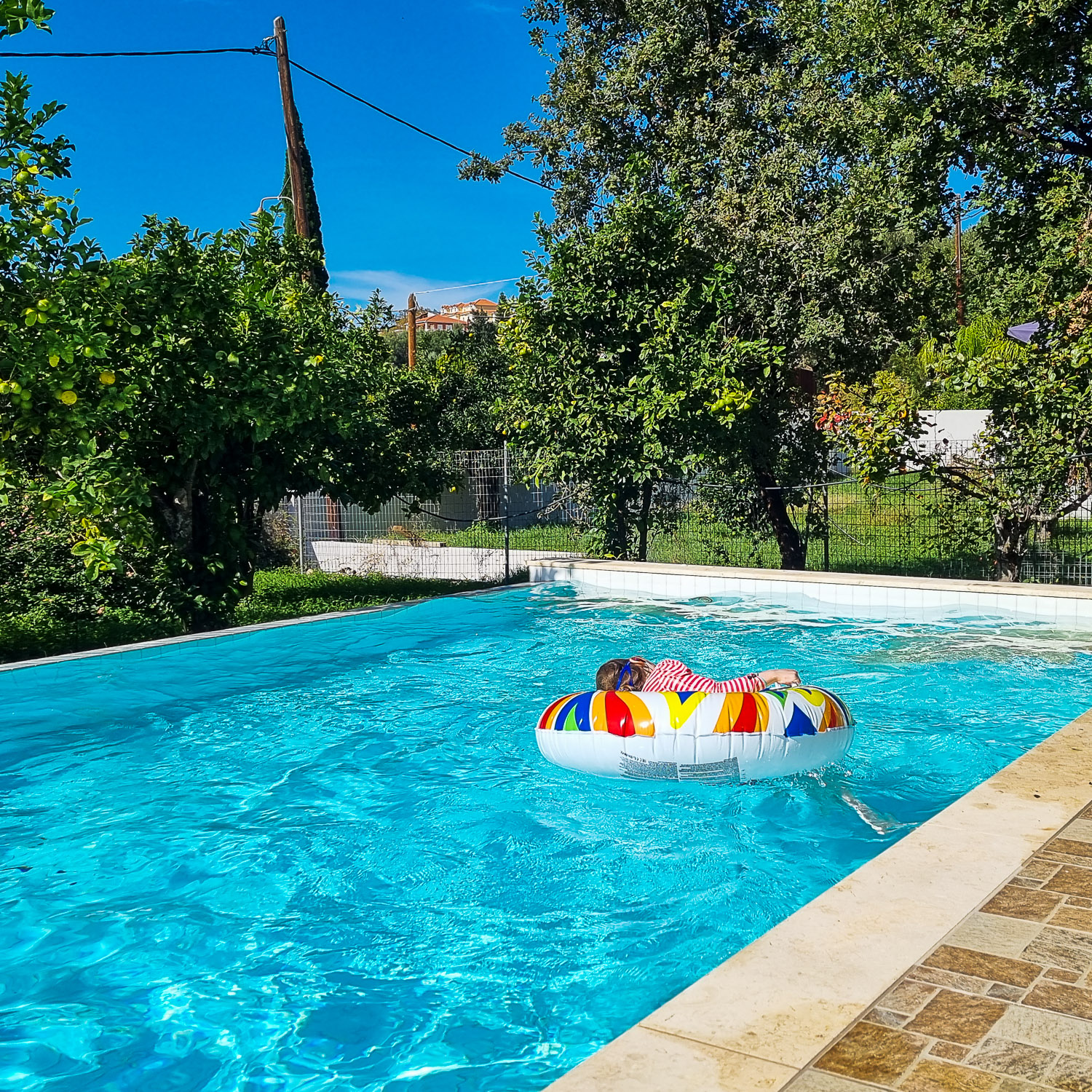 My daughter floats on a brightly coloured inflatable ring in the pool of our villa in Kefalonia - looking back on a decade of family travel
