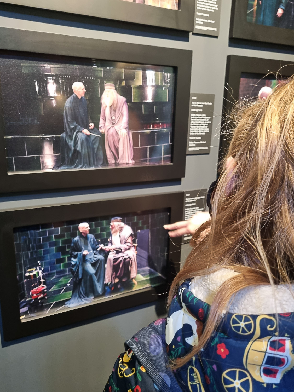 My daughter looks at behind the scenes photos of the actors playing Voldemort and Dumbledore during a visit to London's Harry Potter Photo Exhibition with kids