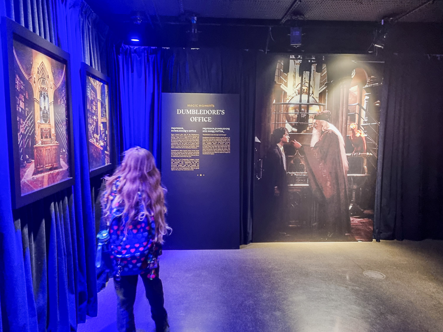 My daughter looks at photos and information about the creation of the set for Dumbledore's office - my review of the Harry Potter Photo Exhibition in Covent Garden, London with kids