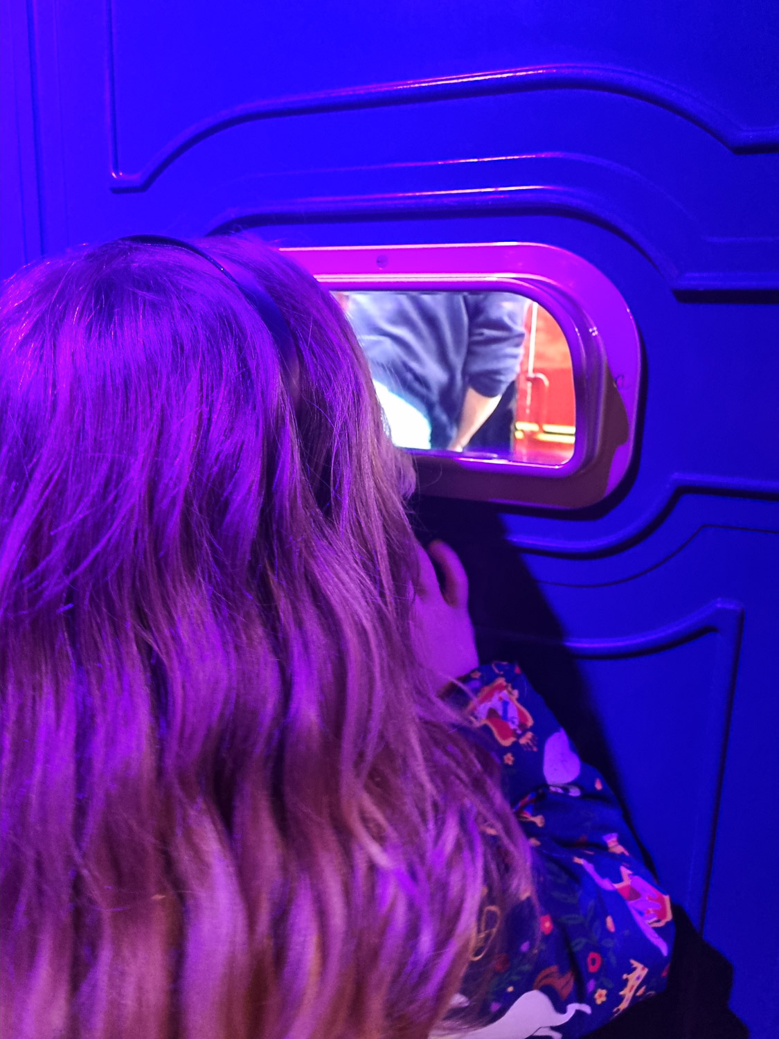 Close up of my daughter peering into an opening showing snippets of video as part of one of the displays during our visit to London's Harry Potter Photographic Exhibition with kids