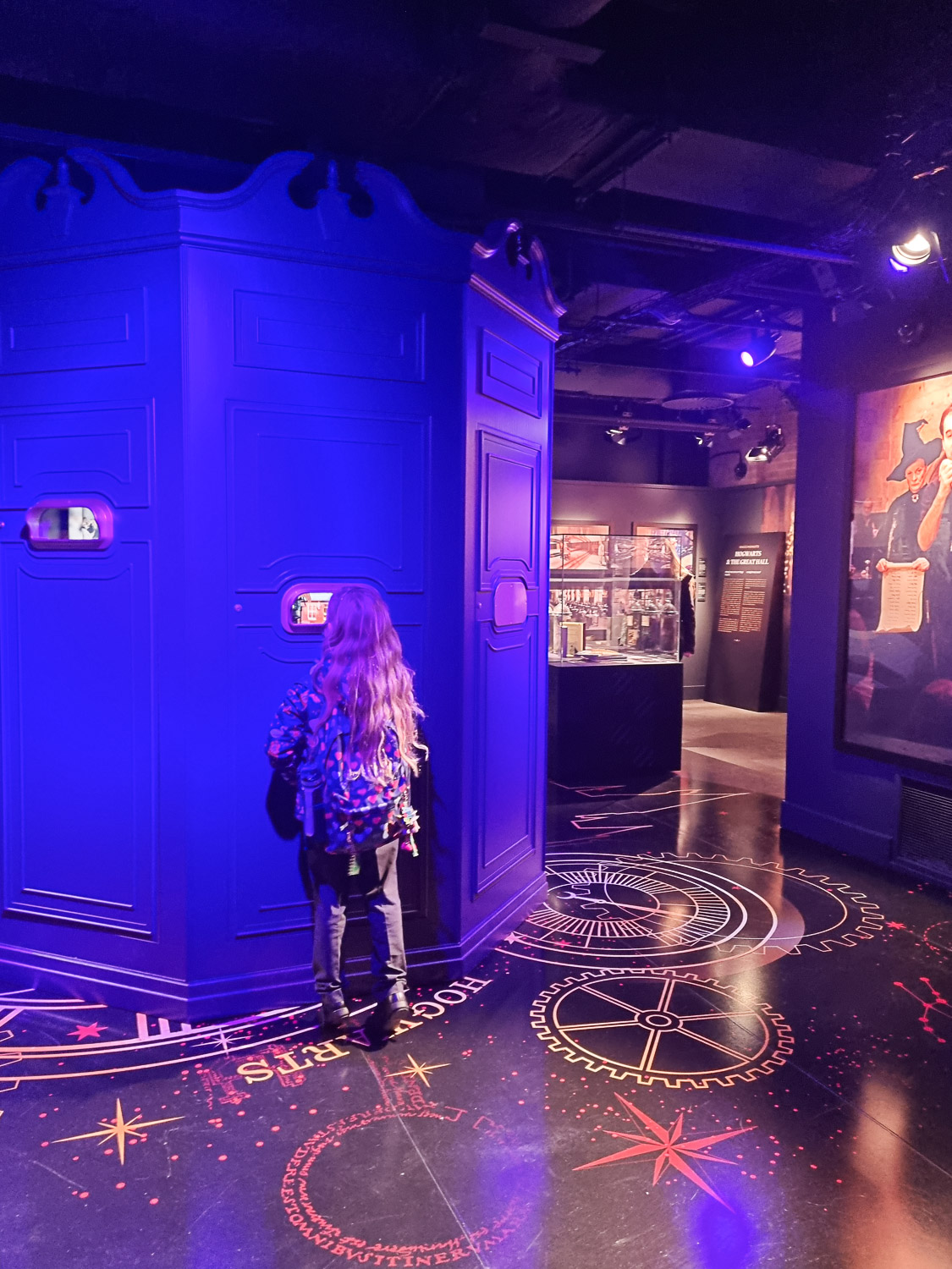 My daughter peers into an opening showing snippets of video as part of one of the displays during our visit to London's Harry Potter Photographic Exhibition with kids