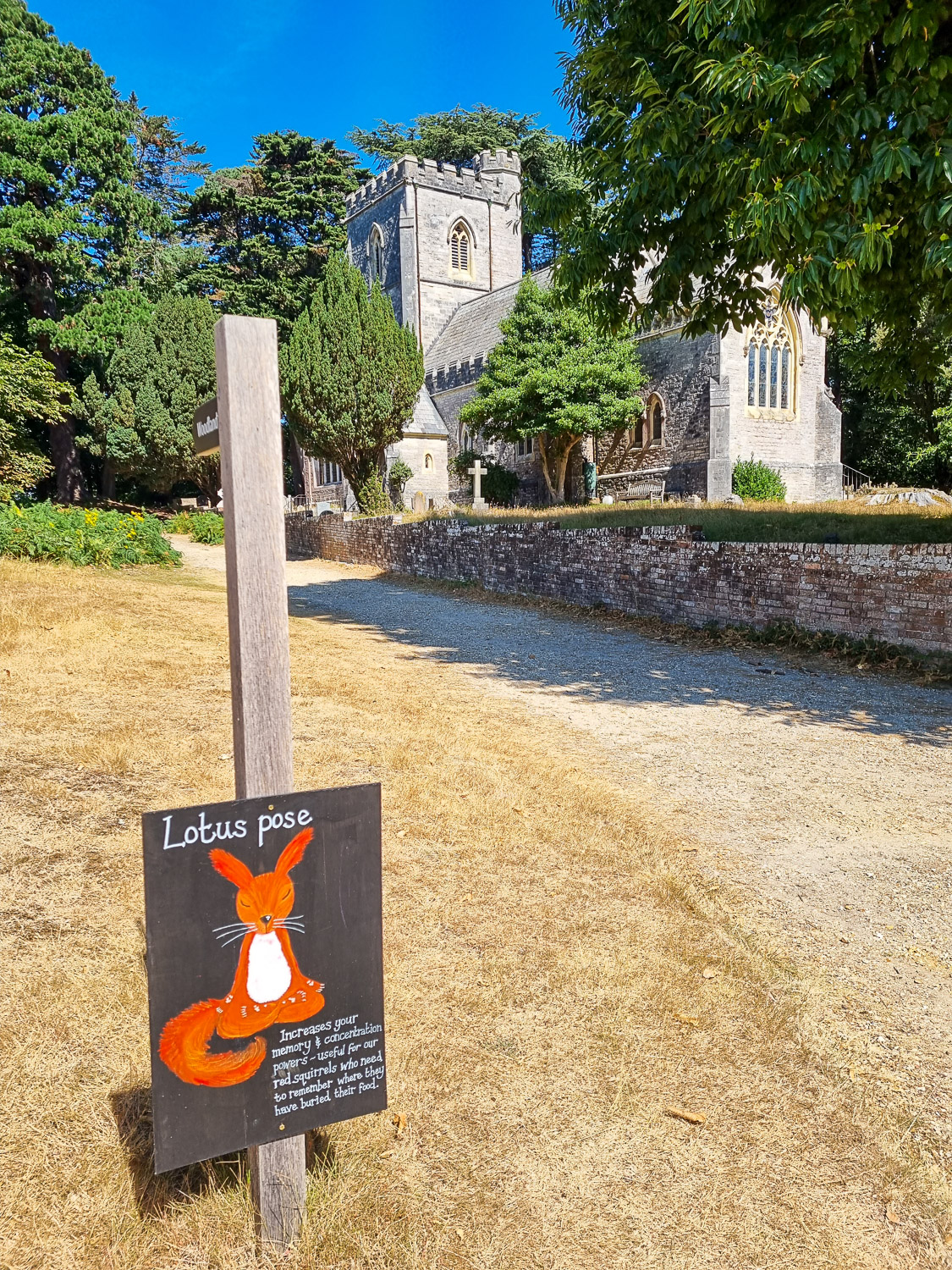 Sign showing squirrel in lotus pose with a church in the background, part of one of the National Trust children's trails you can try during a day out on Brownsea Island with kids