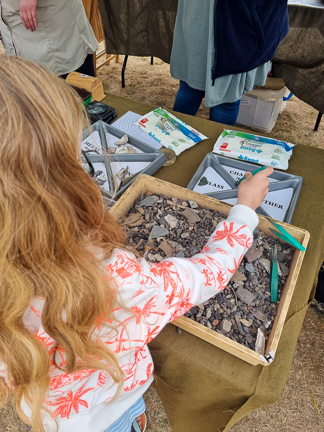 My daughter with a pair of tweezers sorting through a box of stones as part of a fun activity at Corfe Castle run by local archaeologists