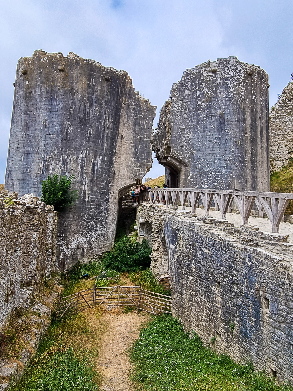 View to the old gatehouse towers, with a missing section in between, and the bridge leading to Corfe Castle