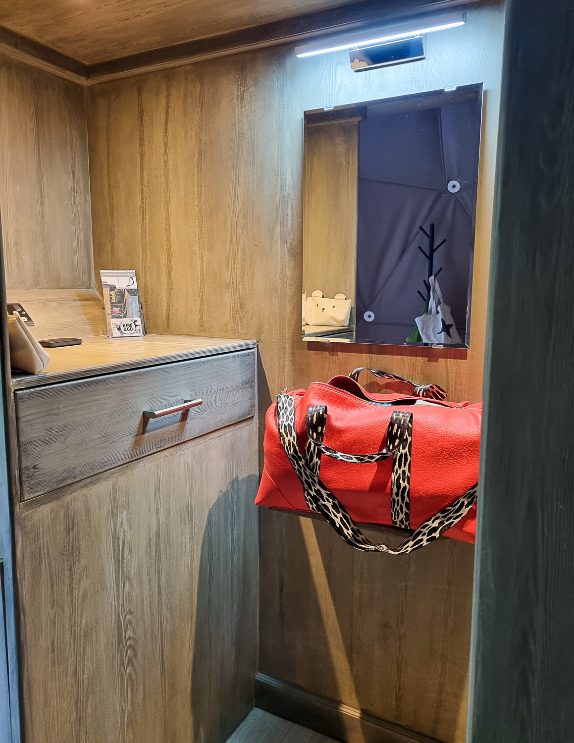 View of the small storage area in Knole Luna Dome with bag on the shelf and small drawer seen - a luxury glamping break in Kent with kids