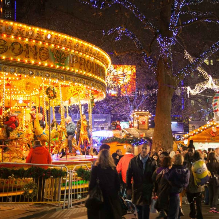 Lit up carousel and crowd by the stalls in Leicester Square - the best Christmas markets in London with kids