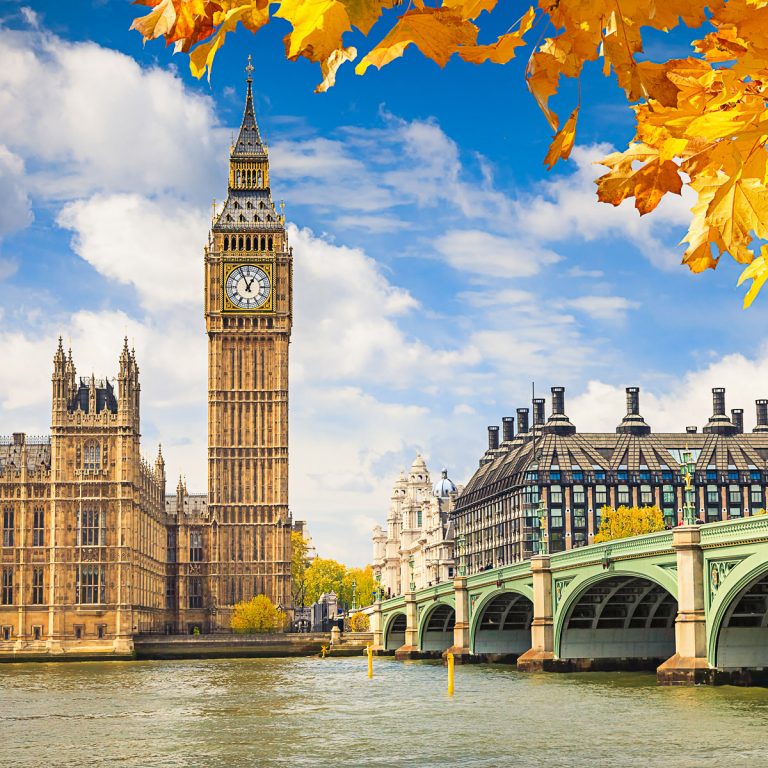 View of Big Ben and Westminster Bridge on a sunny day with orange autumn leaves visible - the best things to do at October half-term in London with kids